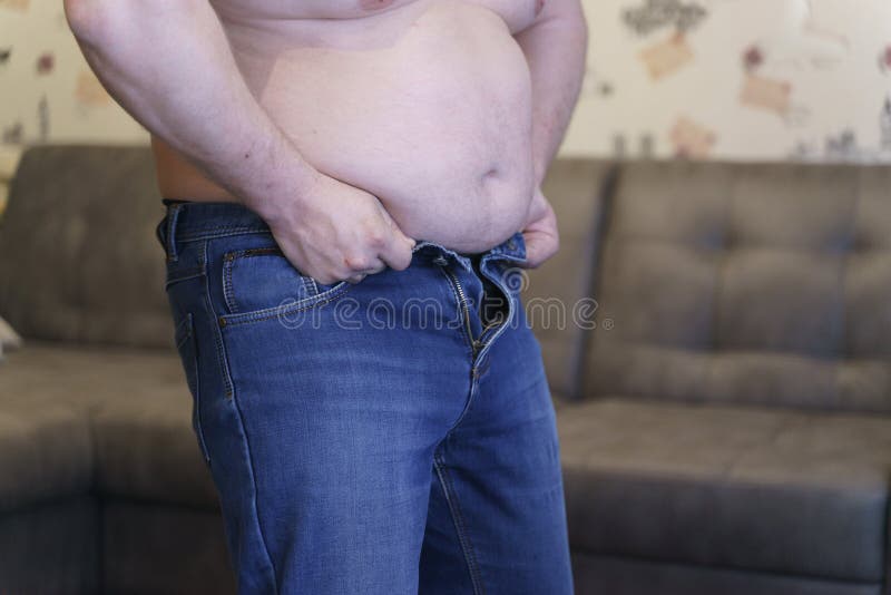 Overweight man trying to fasten too small jean pants. Represent of