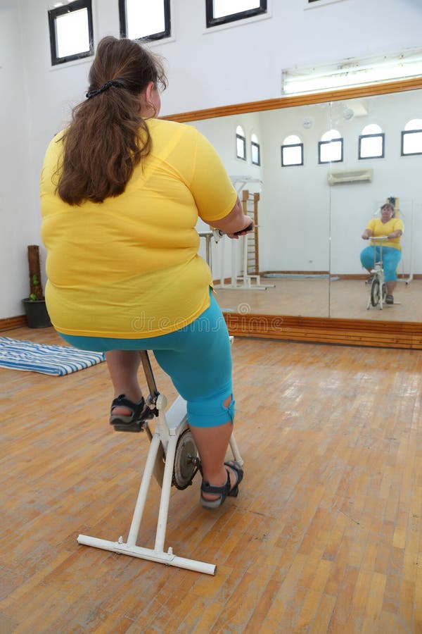 Overweight woman exercising on bike simulator stock photos