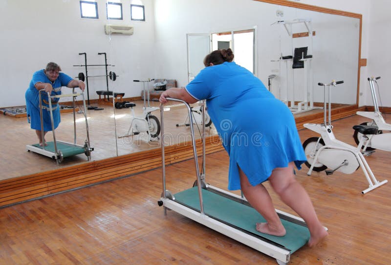 Overweight woman running on trainer treadmill royalty free stock photography