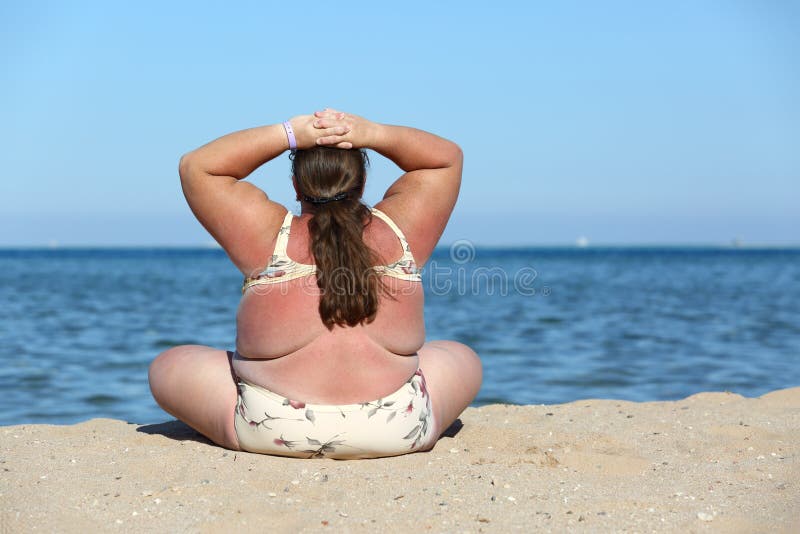 Overweight woman sitting on beach royalty free stock photo
