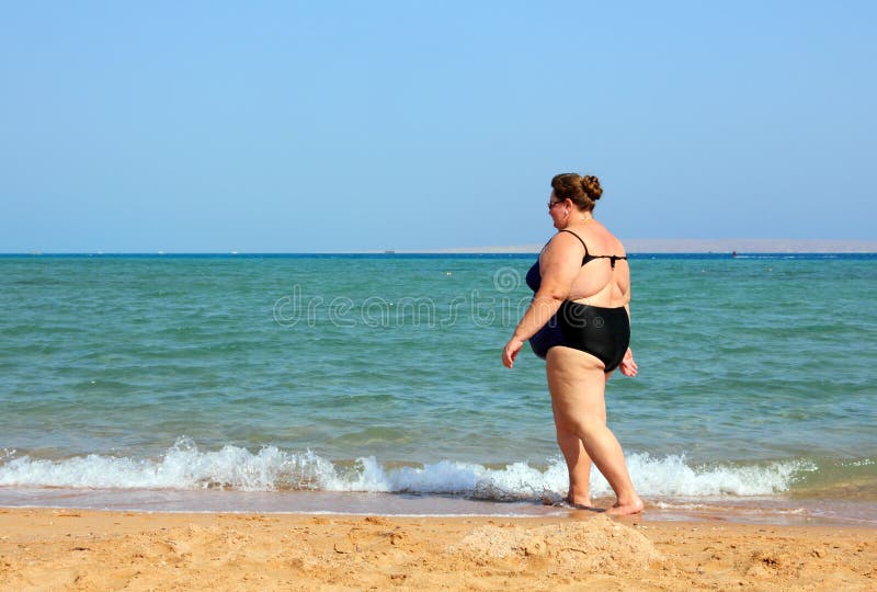 Overweight woman walking on beach royalty free stock images