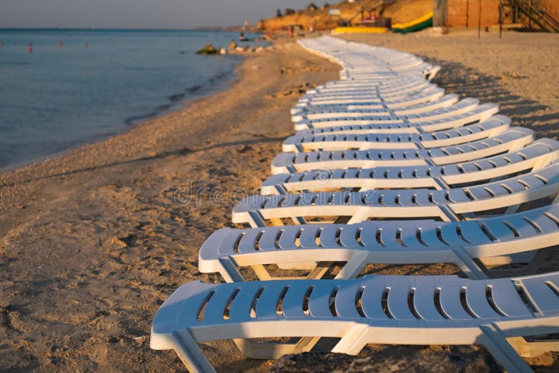 Overzeese toevlucht met lege witte zonlanterfanters Zonsopgang op het strand royalty-vrije stock fotografie Overzeese toevlucht met lege witte zonlanterfanters Zonsopgang op het strand royalty-vrije stock fotografie