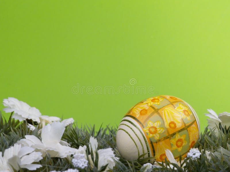 Handpainted daffodil design on easter egg, artificial grass and blossoms, green background. Handpainted daffodil design on easter egg, artificial grass and blossoms, green background