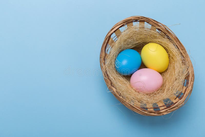 Ovos da páscoa de Colorfull no ninho no fundo azul com espaço imagem de stock royalty free Ovos da páscoa de Colorfull no ninho no fundo azul com espaço imagem de stock royalty free