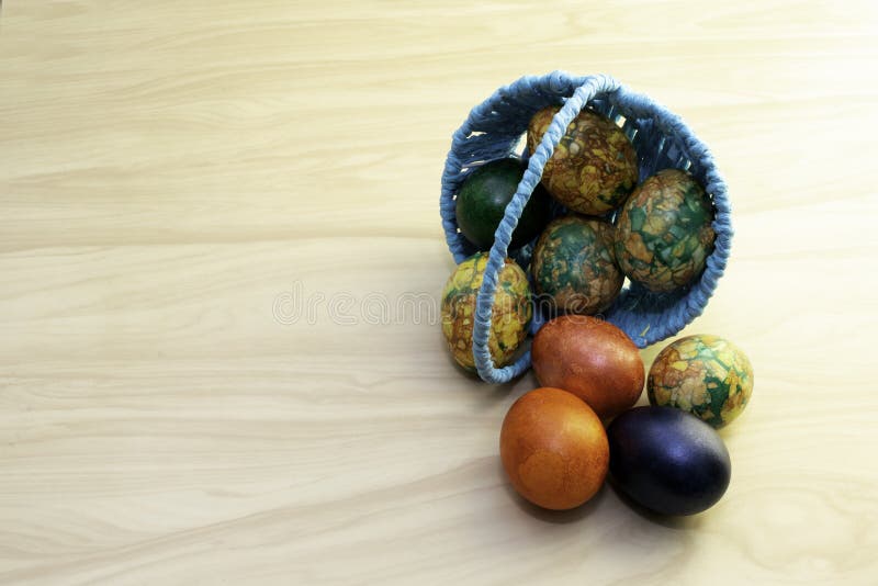 Ovos da páscoa que encontram-se em uma tabela de madeira amarela e em uma cesta azul, pastas da cópia foto de stock royalty free Ovos da páscoa que encontram-se em uma tabela de madeira amarela e em uma cesta azul, pastas da cópia foto de stock royalty free