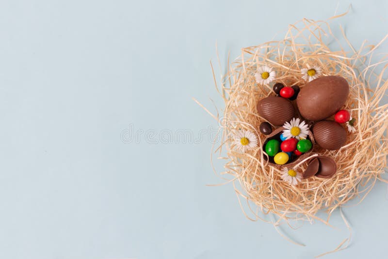 Ovos de Páscoa de Chocolate em um ninho na vista superior de fundo azul pastel e espaço de cópia para seu texto imagens de stock Ovos de Páscoa de Chocolate em um ninho na vista superior de fundo azul pastel e espaço de cópia para seu texto imagens de stock