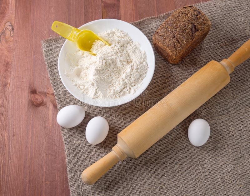 Ovos, farinha e pino do rolo - em um fundo de madeira rústico Ingredientes para produtos da padaria imagem de stock Ovos, farinha e pino do rolo - em um fundo de madeira rústico Ingredientes para produtos da padaria imagem de stock