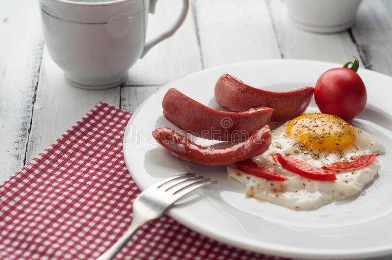 Ovos mexidos em uma placa com partes de tomate e de salsicha imagem de stock Ovos mexidos em uma placa com partes de tomate e de salsicha imagem de stock