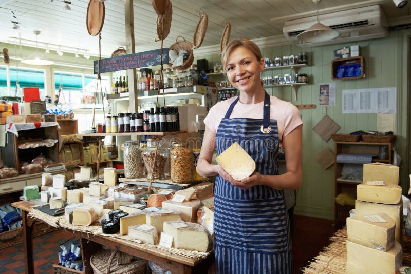 Owner Of Delicatessen Standing In Shop Holding Cheese stock photography