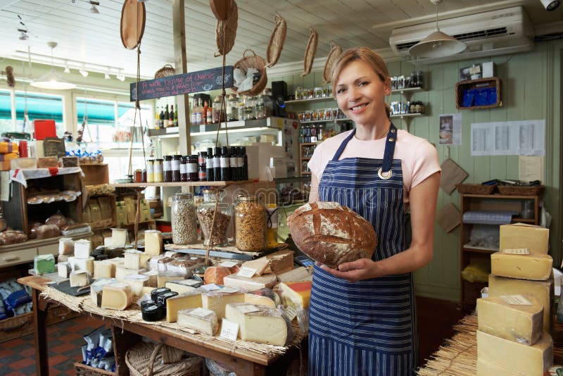 Owner Of Delicatessen Standing In Shop Holding Loaf royalty free stock image