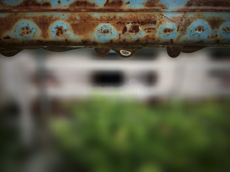 Oxidação quadrada de aço velha do tubo com gotas da água no jardim imagem de stock Oxidação quadrada de aço velha do tubo com gotas da água no jardim imagem de stock