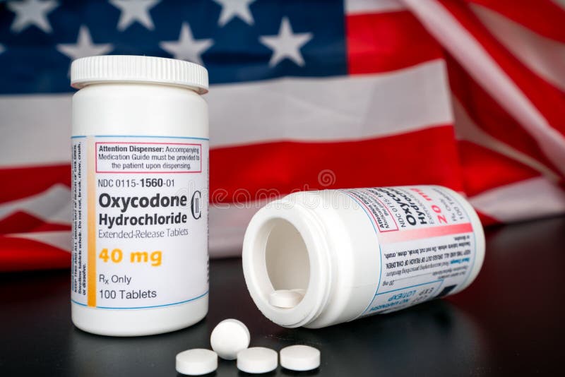 Oxycodone Hydrochloride prescription bottles isolated on black foreground with the american national flag in the background.