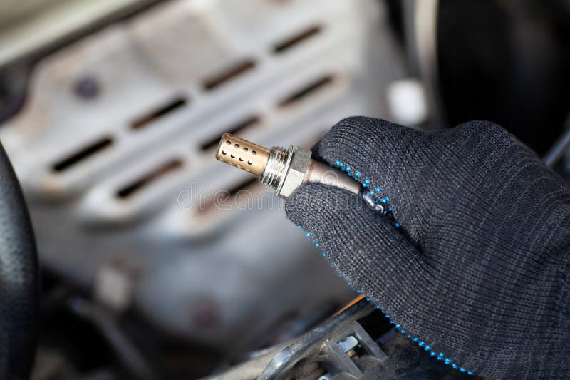 Oxygen sensor for gasoline and diesel engines in the hand against car engine. Mechanic holds oxygen sensor. lambda probe stock images