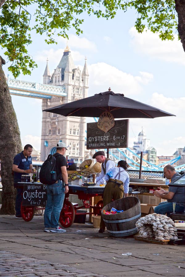 Man selling oysters in an old-fashioned stand by the river of Thames in London. Tower Bridge in the background.