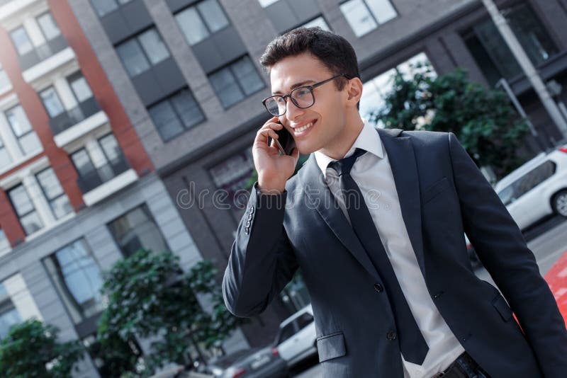 Образ жизни дела Бизнесмен в eyeglasses стоя на улице города говоря на смартфоне смотря в сторону жизнерадостный стоковые изображения Образ жизни дела Бизнесмен в eyeglasses стоя на улице города говоря на смартфоне смотря в сторону жизнерадостный стоковые изображения