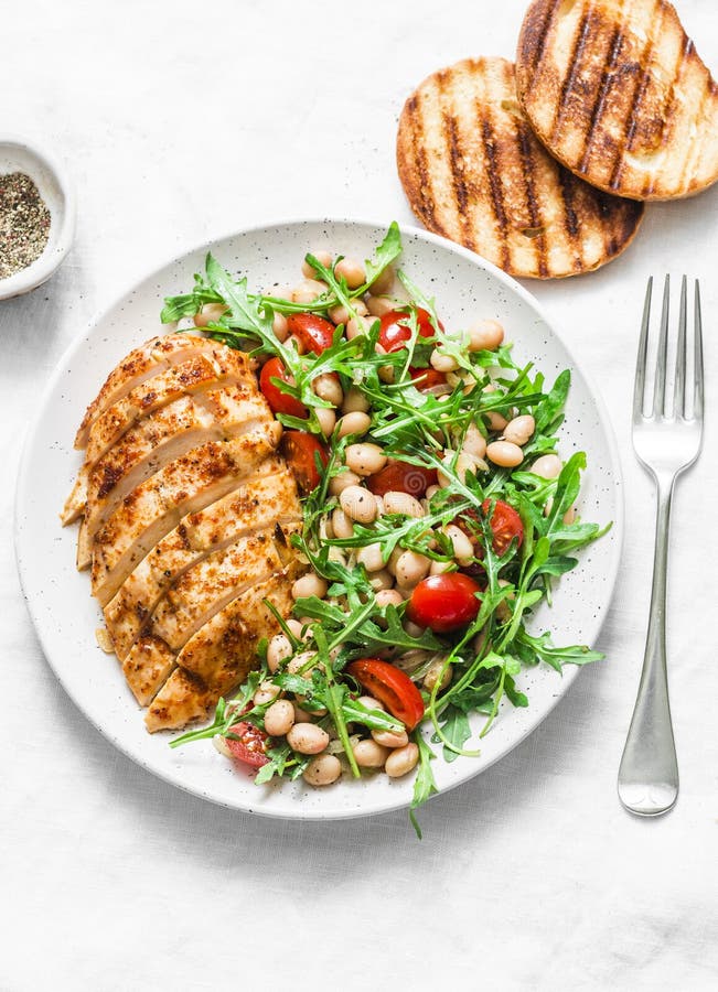 Очень вкусный здоровый обед - испеченные куриная грудка и белые фасоли, arugula, салат томатов вишни на светлой предпосылке стоковые фото Очень вкусный здоровый обед - испеченные куриная грудка и белые фасоли, arugula, салат томатов вишни на светлой предпосылке стоковые фото