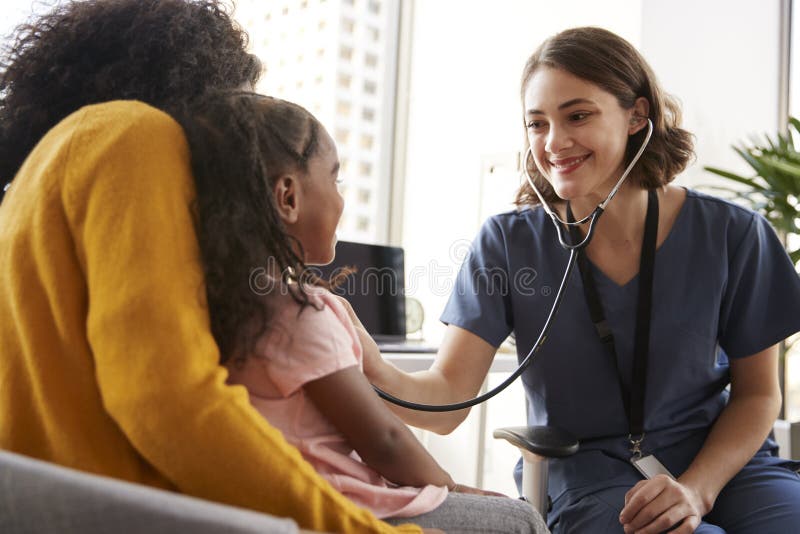 P?diatre f?minin Wearing Scrubs Listening au coffre de filles avec le st?thoscope dans le bureau d'h?pital images libres de droits P?diatre f?minin Wearing Scrubs Listening au coffre de filles avec le st?thoscope dans le bureau d'h?pital images libres de droits