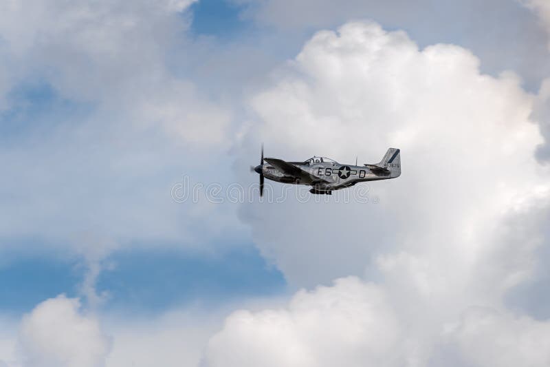 EDEN PRAIRIE MN - JULY 16 2016: P-51 Mustang Sierra Sue II flies amidst clouds at air show. The P-51 Mustang was primarily used as a long-range fighter during World War II. EDEN PRAIRIE MN - JULY 16 2016: P-51 Mustang Sierra Sue II flies amidst clouds at air show. The P-51 Mustang was primarily used as a long-range fighter during World War II.