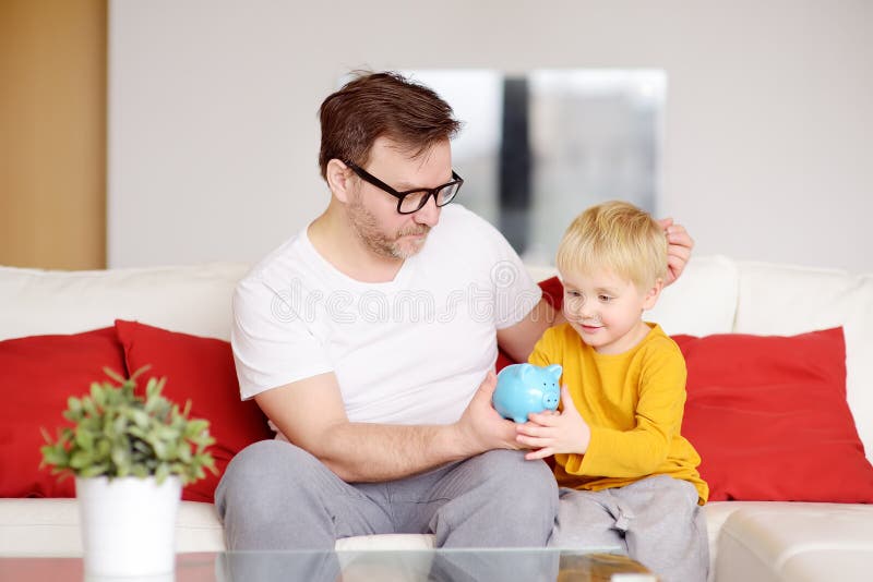 P?re et fils mettant la pi?ce de monnaie dans la tirelire ?ducation des enfants dans l'instruction financi?re images stock P?re et fils mettant la pi?ce de monnaie dans la tirelire ?ducation des enfants dans l'instruction financi?re images stock