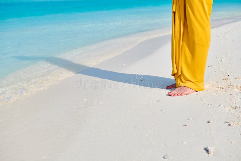 P?s da mulher no vestido amarelo na praia tropical fotografia de stock P?s da mulher no vestido amarelo na praia tropical fotografia de stock