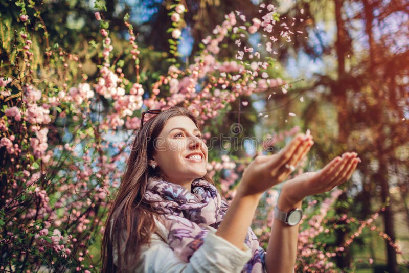 P?tales de lancement de fleur de belle femme heureuse appr?ciant le jardin de floraison de ressort Avoir l'amusement photographie stock libre de droits P?tales de lancement de fleur de belle femme heureuse appr?ciant le jardin de floraison de ressort Avoir l'amusement photographie stock libre de droits