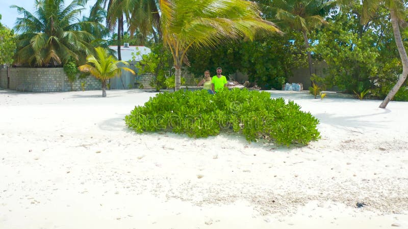Paar auf einem tropischen Strand mit blauem Wasser, Palmen und weißem Sand auf der lokalen Insel Bodufolhudhoo in Malediven stock video footage