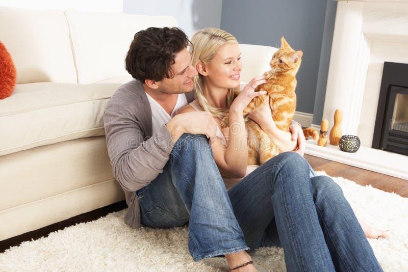 Paar dat thuis het Spelen met de Kat van het Huisdier neemt stock afbeelding Paar dat thuis het Spelen met de Kat van het Huisdier neemt stock afbeelding