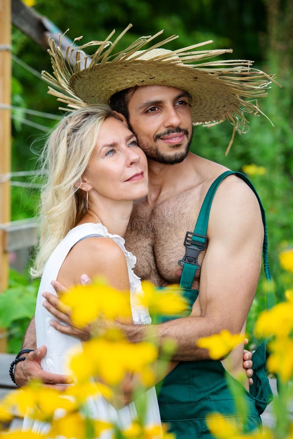 Paar die elkaar buiten in de tuin koesteren stock foto Paar die elkaar buiten in de tuin koesteren stock foto