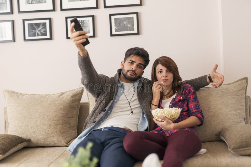 Paar die op een spel op TV letten en popcorn eten royalty-vrije stock foto Paar die op een spel op TV letten en popcorn eten royalty-vrije stock foto
