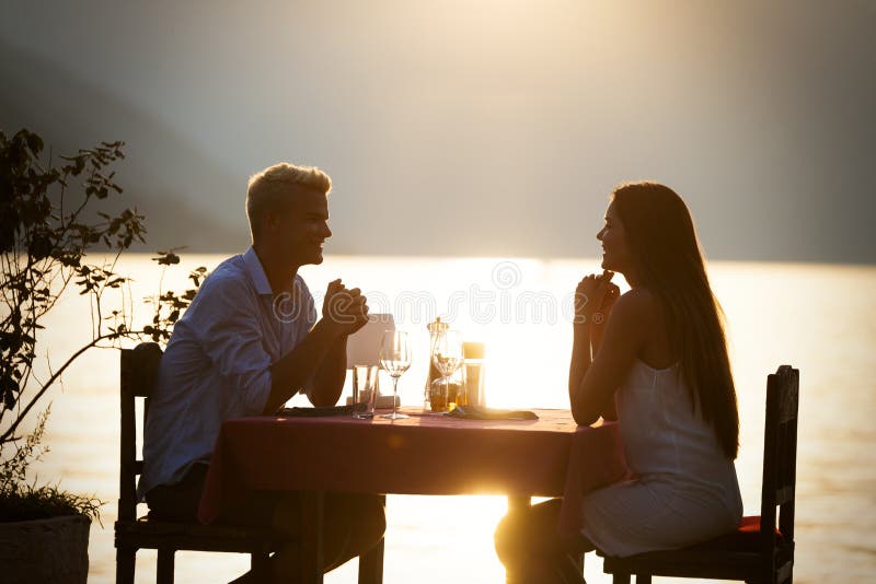 Paar die romantisch zonsondergangdiner bij de tropische toevlucht delen stock foto Paar die romantisch zonsondergangdiner bij de tropische toevlucht delen stock foto