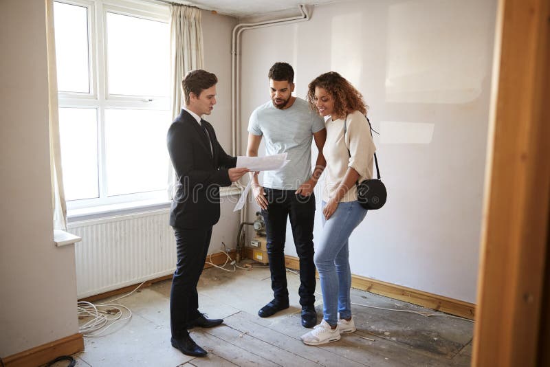 Couple Buying House For The First Time Looking At Survey With Realtor. Couple Buying House For The First Time Looking At Survey With Realtor