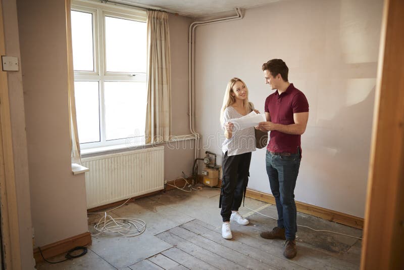Paar-kaufendes Haus für das erste Mal, das Haus-Übersicht im Raum erneuert zu werden betrachtet lizenzfreie stockfotos Paar-kaufendes Haus für das erste Mal, das Haus-Übersicht im Raum erneuert zu werden betrachtet lizenzfreie stockfotos