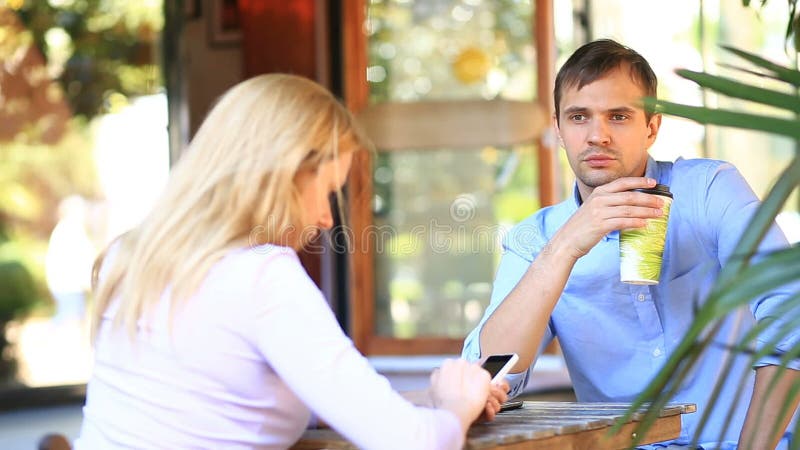 Paar in liefde in een openluchtkoffie Man en mooie vrouw op een datum Iedereen bekijkt zijn mobiele telefoon