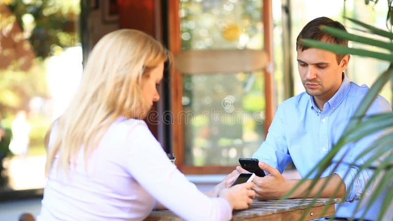 Paar in liefde in een openluchtkoffie Man en mooie vrouw op een datum Iedereen bekijkt zijn mobiele telefoon
