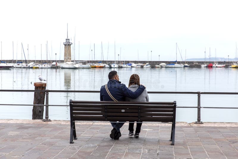 Paar in liefde op de kusten van Meer Garda, Desenzano Di Garda, Italië In liefdepaar op de waterkant Paar die op een bank koester royalty-vrije stock foto Paar in liefde op de kusten van Meer Garda, Desenzano Di Garda, Italië In liefdepaar op de waterkant Paar die op een bank koester royalty-vrije stock foto
