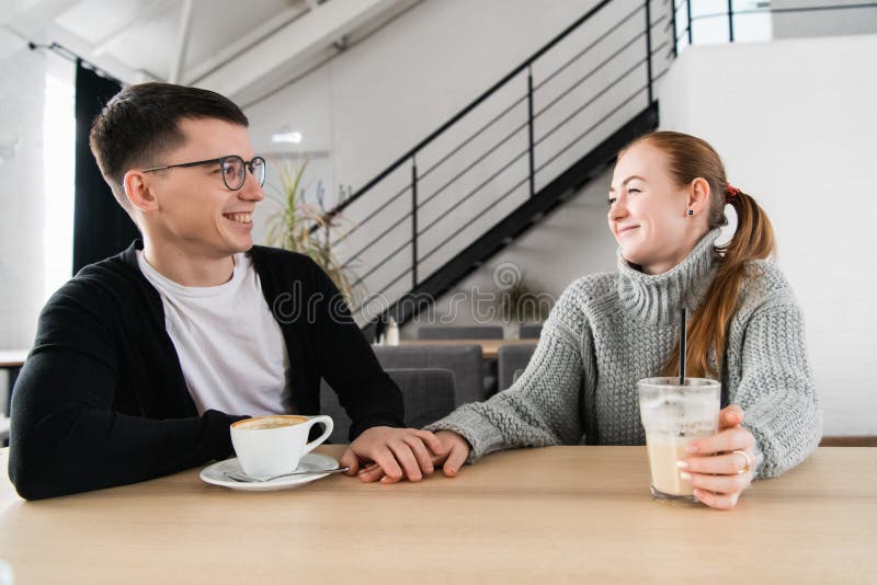 Paar in liefdezitting in koffie die elkaar bekijken en handen houden royalty-vrije stock afbeeldingen Paar in liefdezitting in koffie die elkaar bekijken en handen houden royalty-vrije stock afbeeldingen