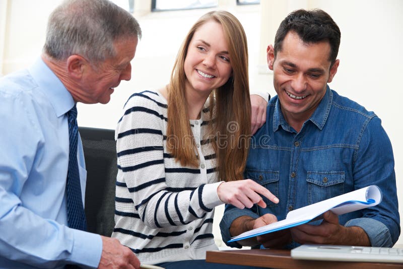 Paar met Financiële Adviseur die Document in Bureau bestuderen stock foto's Paar met Financiële Adviseur die Document in Bureau bestuderen stock foto's