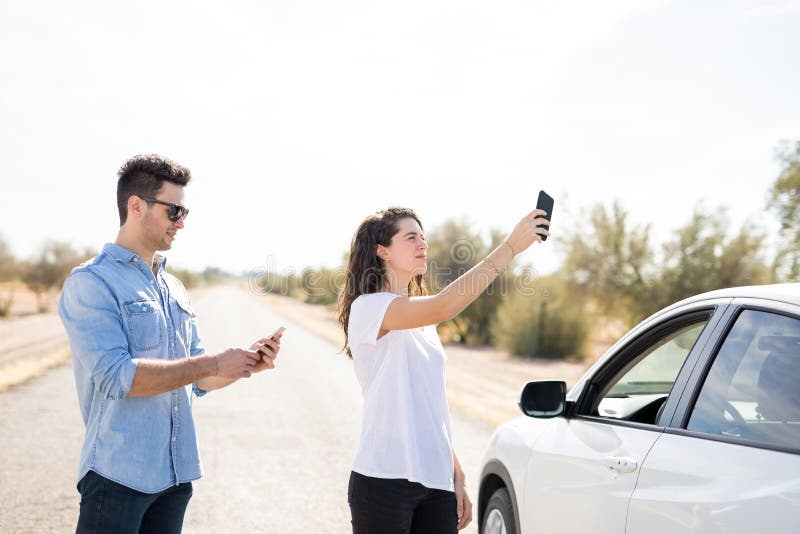 Paar met gebroken auto die naar telefoondekking zoeken royalty-vrije stock afbeelding Paar met gebroken auto die naar telefoondekking zoeken royalty-vrije stock afbeelding