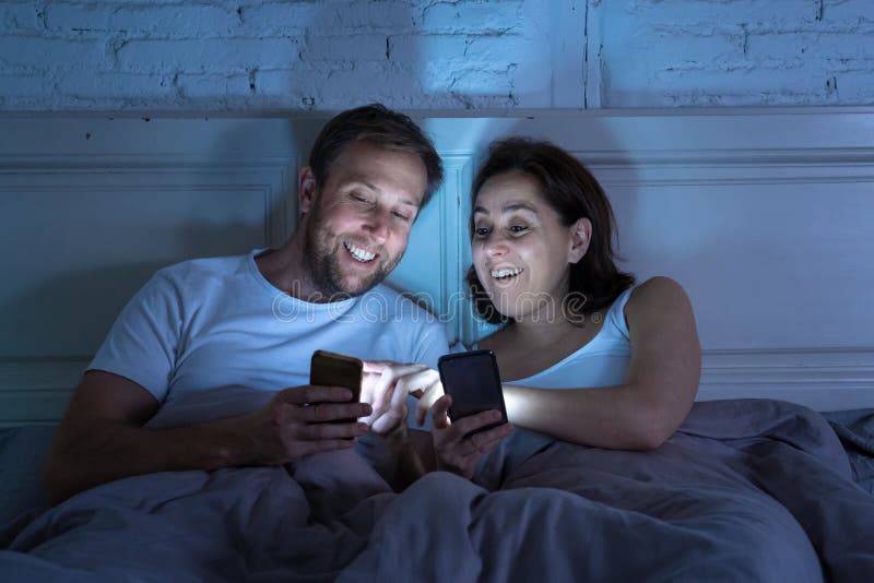 Paar op mobiele telefoons in bed laat bij nacht die van sociale netwerk, spelen en Internet-verbinding genieten stock afbeeldingen Paar op mobiele telefoons in bed laat bij nacht die van sociale netwerk, spelen en Internet-verbinding genieten stock afbeeldingen