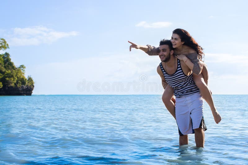Paar-Strand-Sommer-Ferien, Mann-Carry Woman Point Finger To-Kopien-Raum-schöner junger glücklicher Mann und Frauen-Lächeln lizenzfreies stockbild Paar-Strand-Sommer-Ferien, Mann-Carry Woman Point Finger To-Kopien-Raum-schöner junger glücklicher Mann und Frauen-Lächeln lizenzfreies stockbild