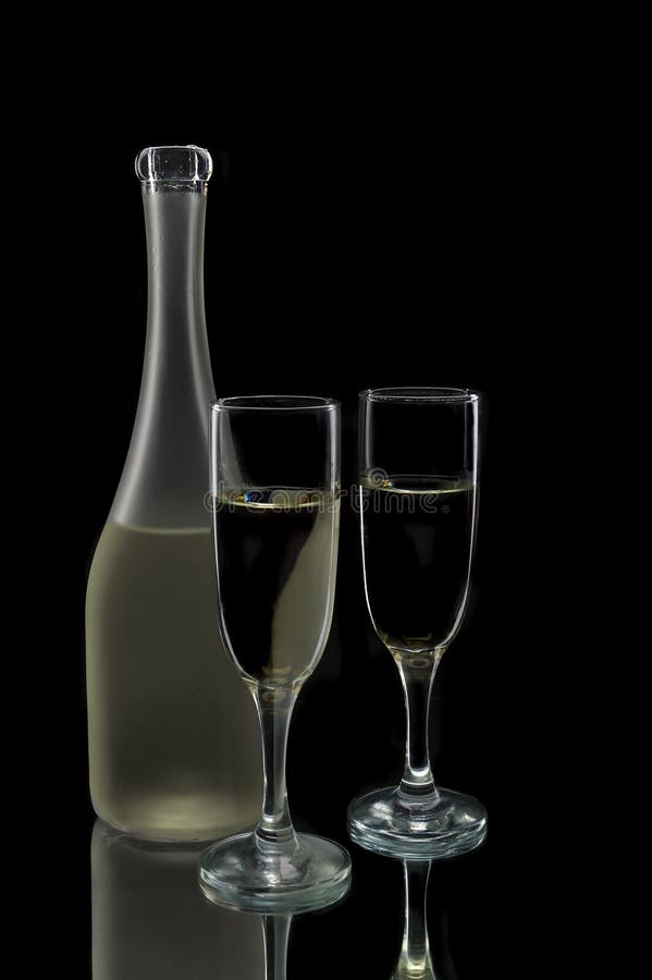 Pair of wine flutes and wine bottle against a black background. Pair of wine flutes and wine bottle against a black background