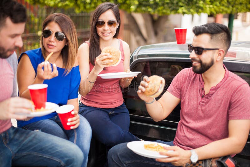 Paare, die Cheeseburger an einem Grill essen lizenzfreies stockbild Paare, die Cheeseburger an einem Grill essen lizenzfreies stockbild