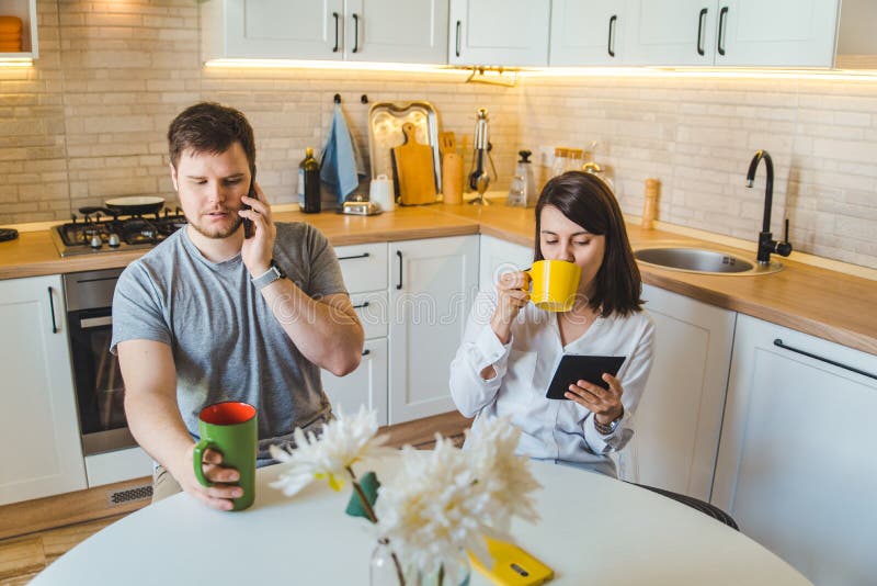 Paare, die morgens an der Küche trinkt Teelesenachrichten sitzen lizenzfreie stockbilder Paare, die morgens an der Küche trinkt Teelesenachrichten sitzen lizenzfreie stockbilder