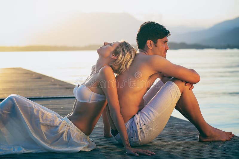 Paare, die Sonnenunterganglicht auf einem Pier genießen lizenzfreie stockfotografie Paare, die Sonnenunterganglicht auf einem Pier genießen lizenzfreie stockfotografie