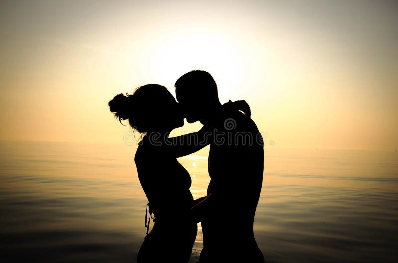 Paare, die am Strand bei Sonnenuntergang küssen stockfotografie Paare, die am Strand bei Sonnenuntergang küssen stockfotografie