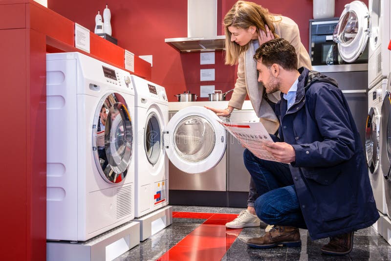 Paare, die Waschmaschine am Grossmarkt wählen lizenzfreie stockbilder