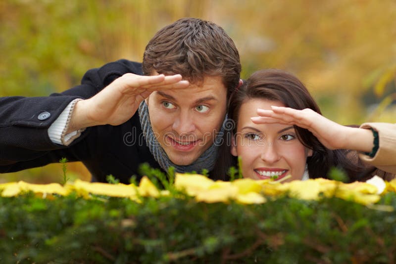 Happy couple looking over a hedge in autumn. Happy couple looking over a hedge in autumn