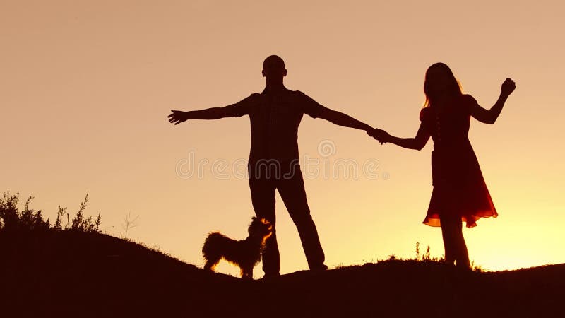 Paare im Liebestanzenschattenbild am Sonnenuntergang und am Küssen Liebevoller Mann und Frau mit Hundetanzen silhouettieren Zeitl