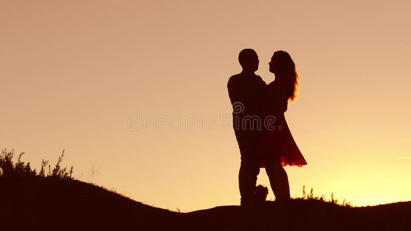 Paare im Liebestanzenschattenbild am Sonnenuntergang- und Naturküssen Liebevoller Mann und Frau mit Hundetanzen silhouettieren la