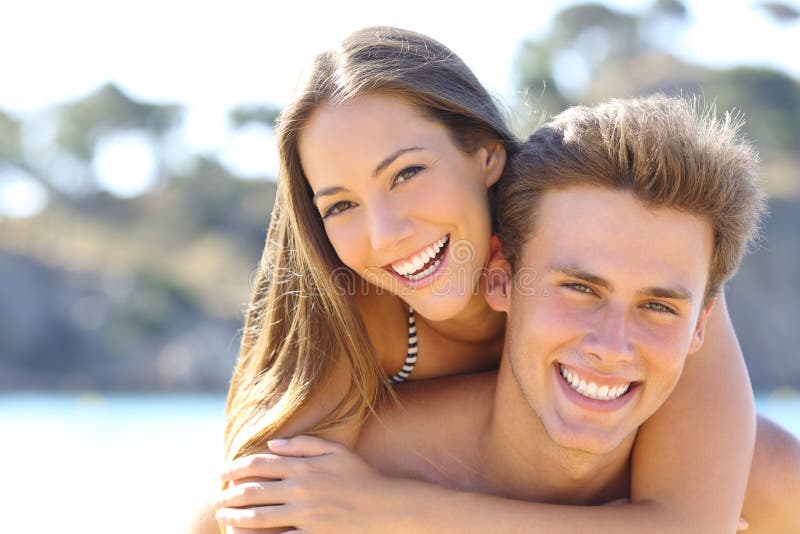 Paare mit dem perfekten Lächeln, das auf dem Strand aufwirft